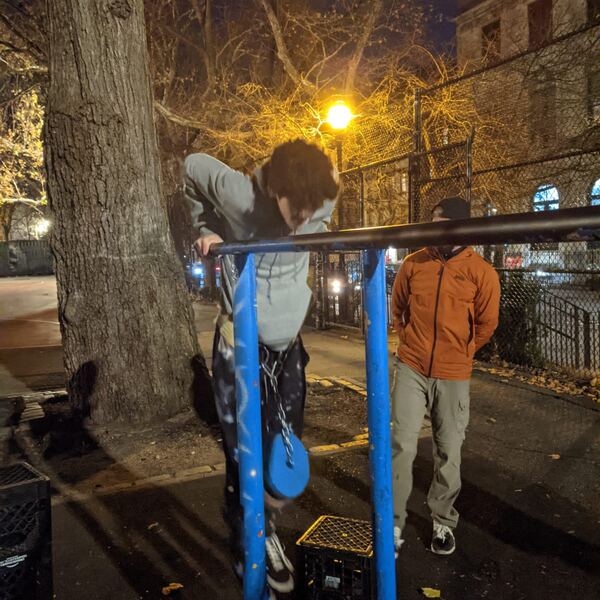 Someone training on the bars at night under a streetlight