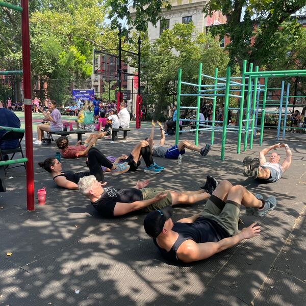 A group doing sit-ups together next to the bars in summer